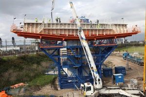 Steigerkeuring op bouwplaats met controleur die verankering en stabiliteit van steiger inspectert